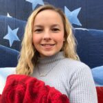 teen girl by flag holding a blanket
