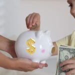 child adding money to piggy bank