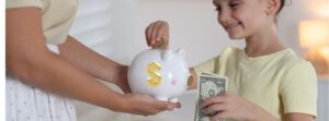 child adding money to piggy bank