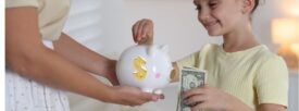 child adding money to piggy bank